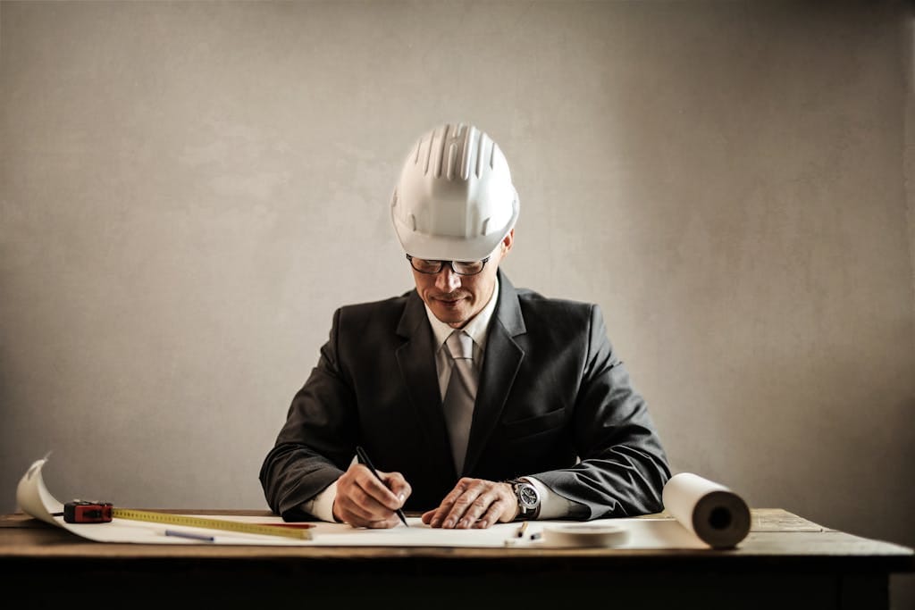 Engineer in a suit drafting architectural plans at a desk indoors. commercial building construction.